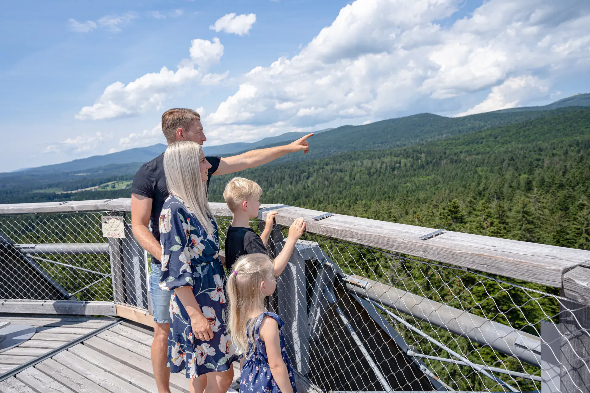 Familie am Geländer des Baumwipfelpfads mit Blick über die Wälder des Bayerischen Waldes