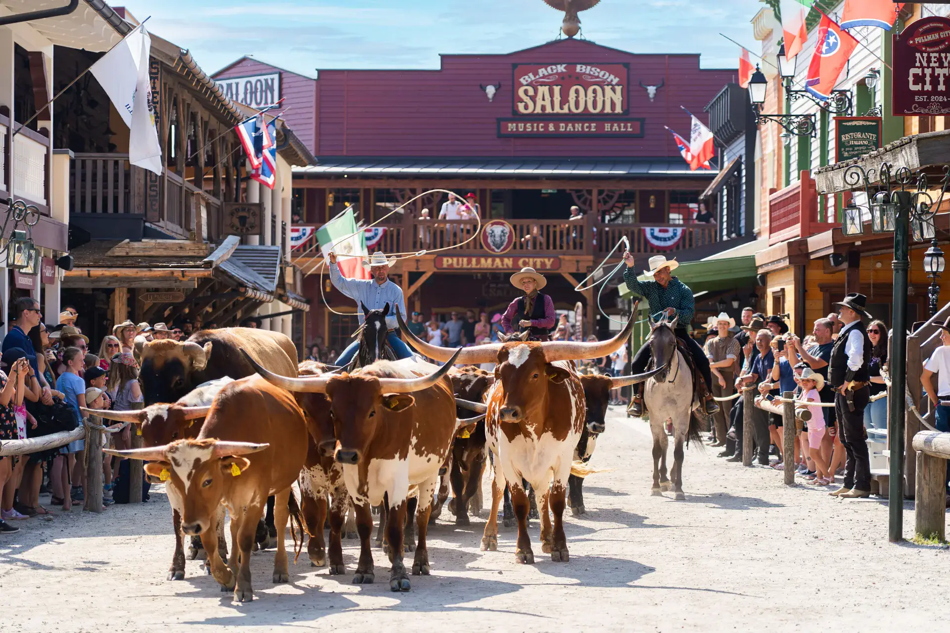 Rindertrieb mit Longhorn-Rindern und Cowboys auf der Main Street von Pullman City, Zuschauer am Straßenrand