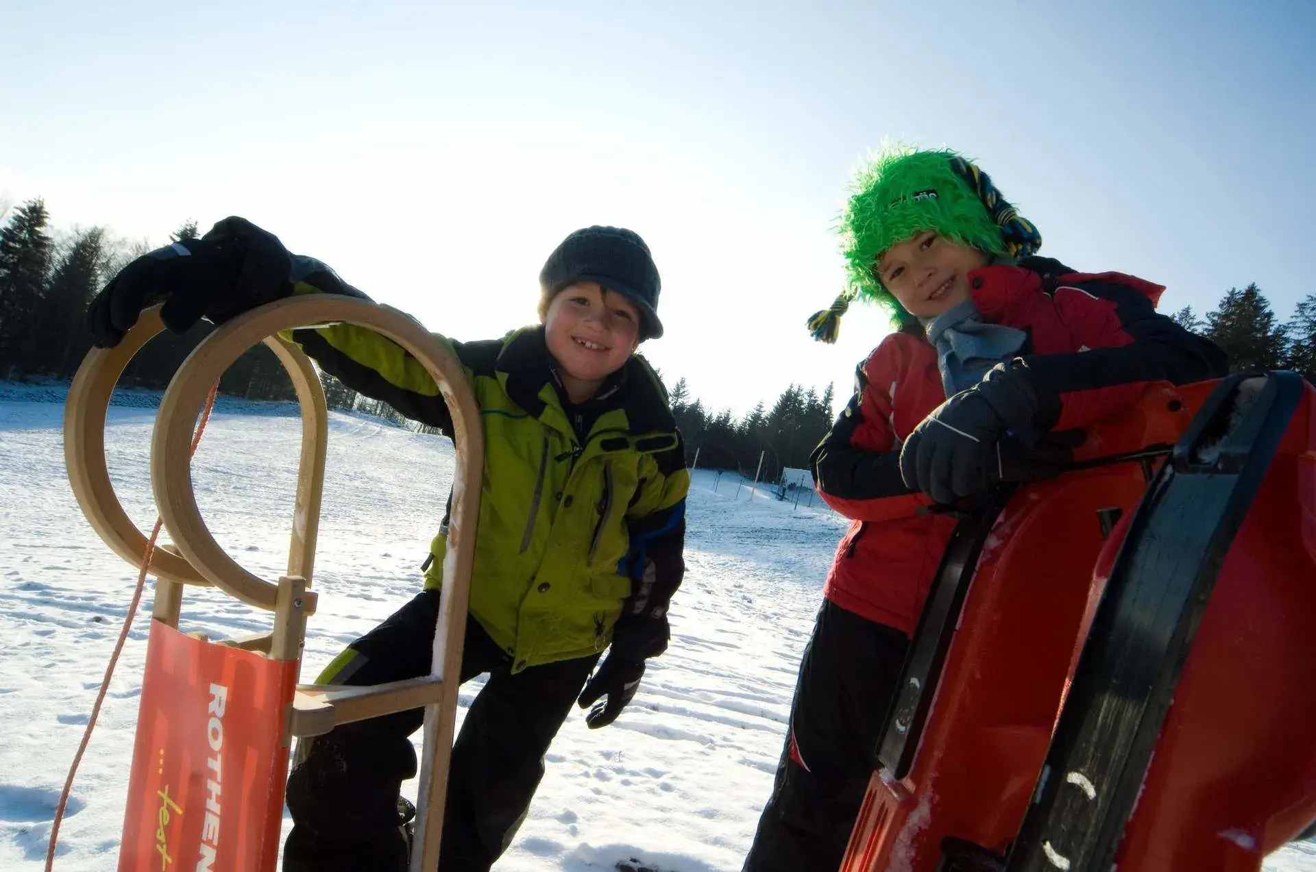 Zwei Kinder mit Schlitten im Schnee am Steinberglift