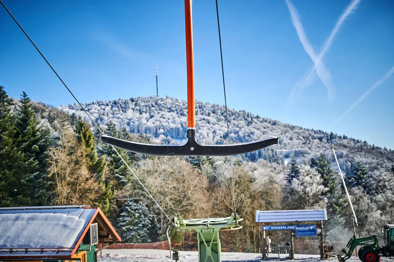 Schlepplift am Steinberg vor verschneitem Wald, unten das Kinderland